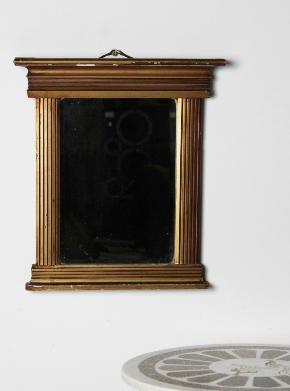 An early 19th century Regency giltwood pier mirror with reeded pilaster sides, a stepped architectural cornice, and foxed glass mirror plate. View III