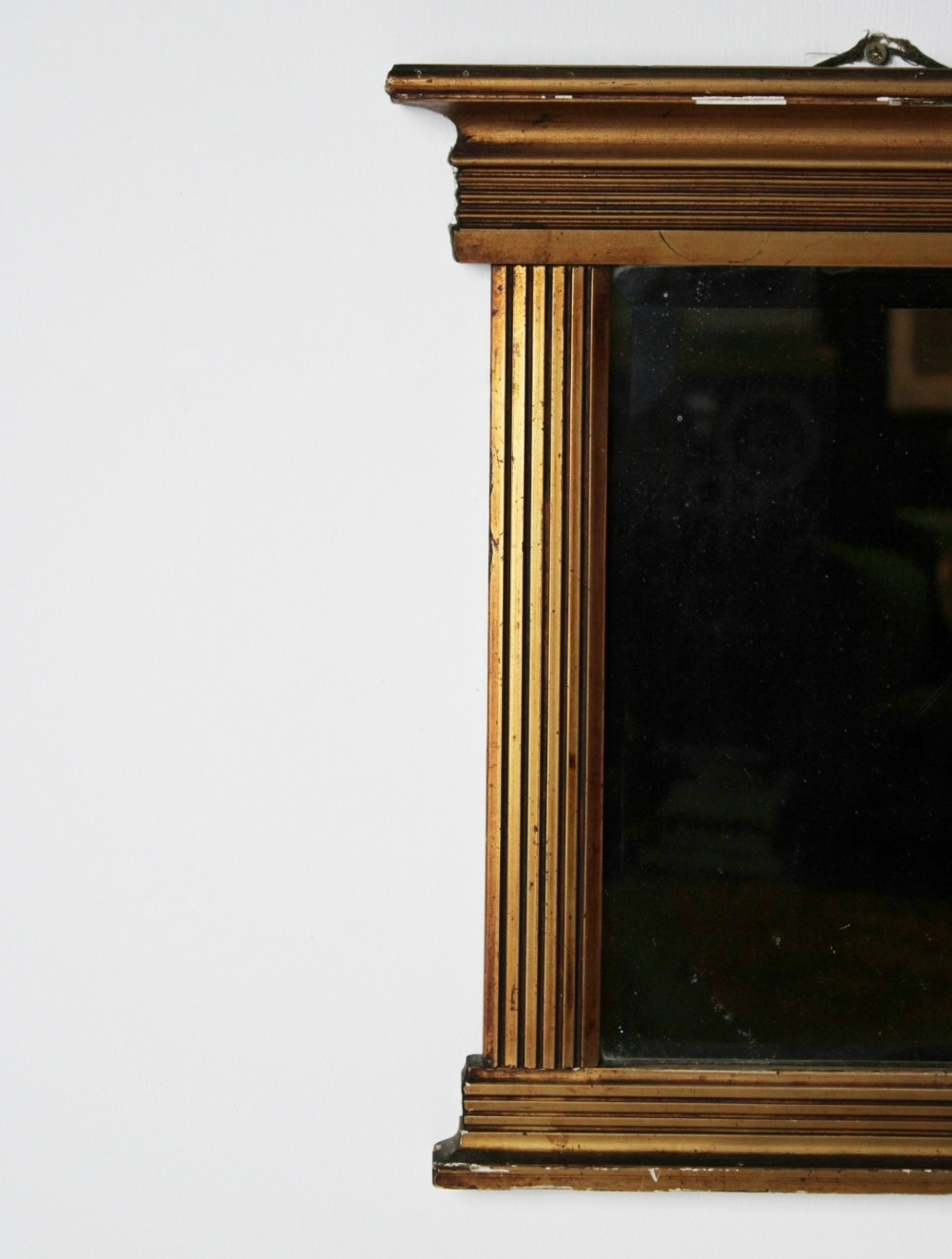 An early 19th century Regency giltwood pier mirror with reeded pilaster sides, a stepped architectural cornice, and foxed glass mirror plate. View IV