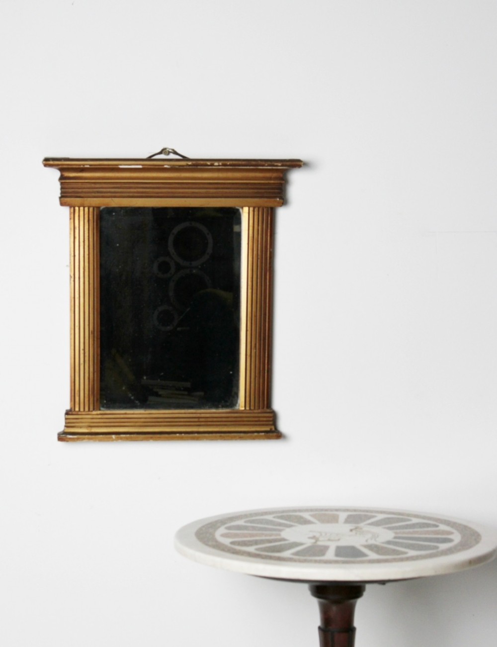 An early 19th century Regency giltwood pier mirror with reeded pilaster sides, a stepped architectural cornice, and foxed glass mirror plate.