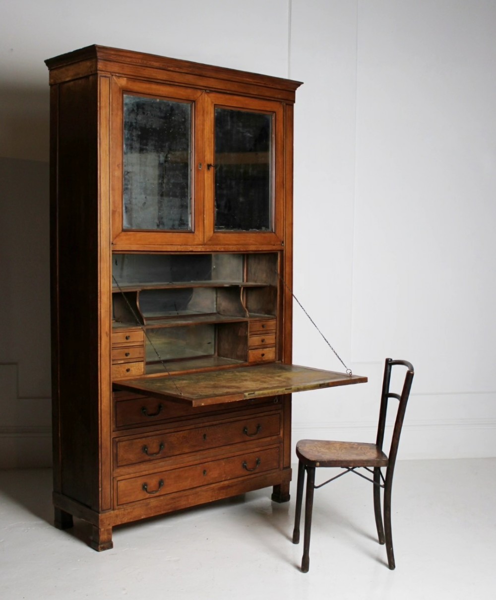 A tall 19th-century fruitwood secretaire cabinet featuring a glazed double-door upper section, a fall-front writing flap, and three long drawers below. View II