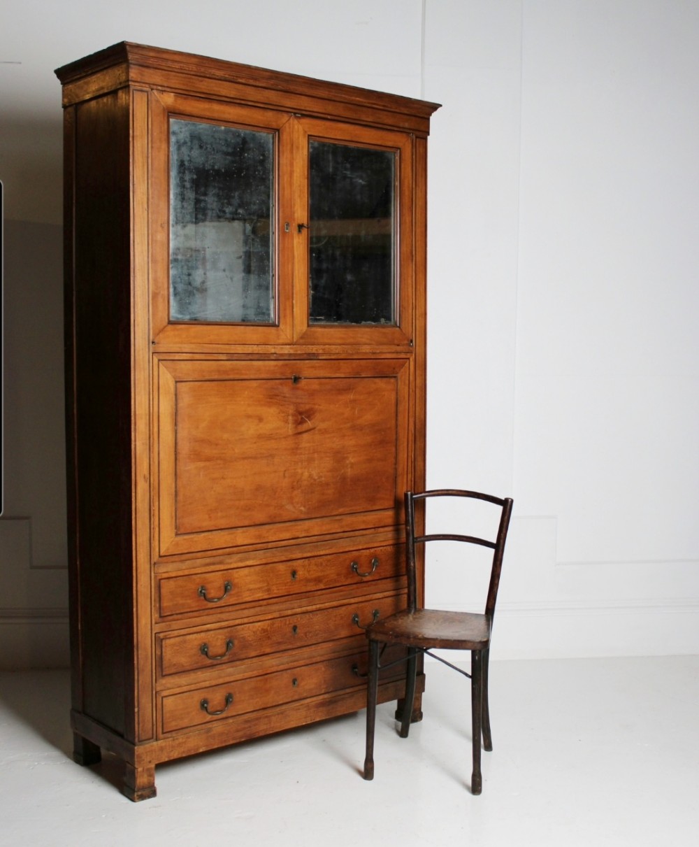 A tall 19th-century fruitwood secretaire cabinet featuring a glazed double-door upper section, a fall-front writing flap, and three long drawers below.
