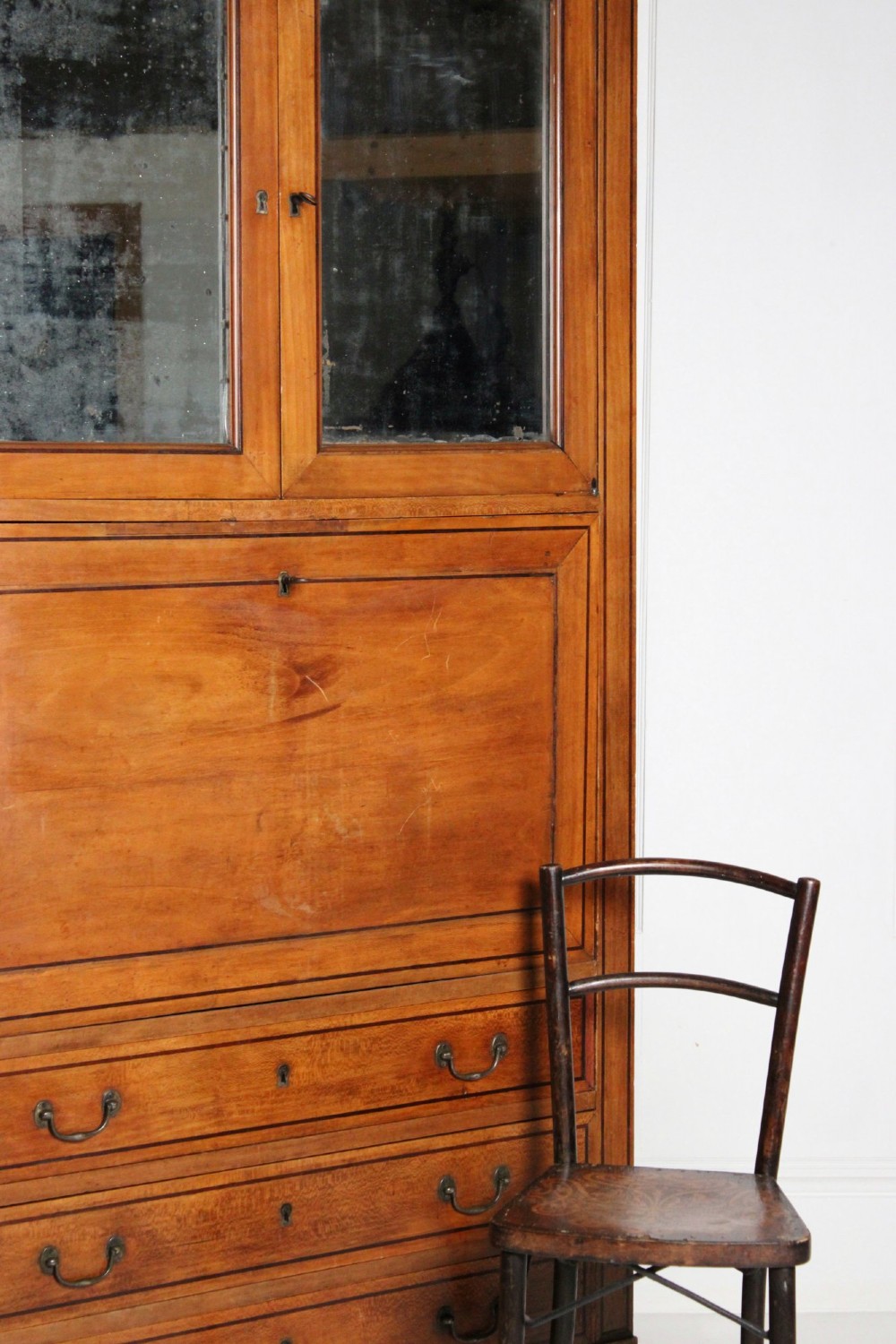 A tall 19th-century fruitwood secretaire cabinet featuring a glazed double-door upper section, a fall-front writing flap, and three long drawers below. View VIII