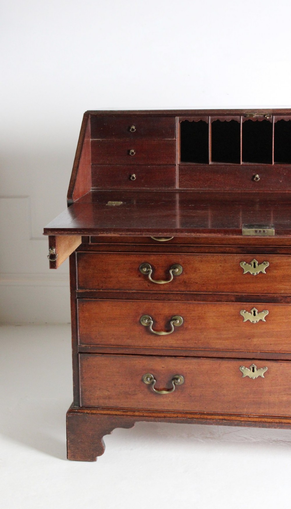 A George III mahogany fall front bureau featuring four graduated drawers with brass handles, resting on bracket feet. View II