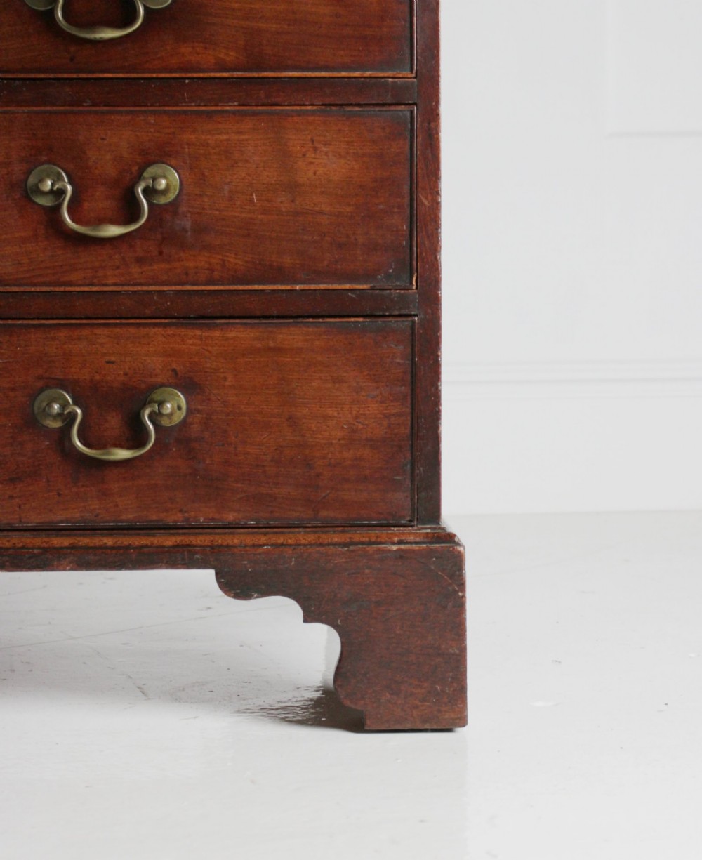 A George III mahogany fall front bureau featuring four graduated drawers with brass handles, resting on bracket feet. View IV