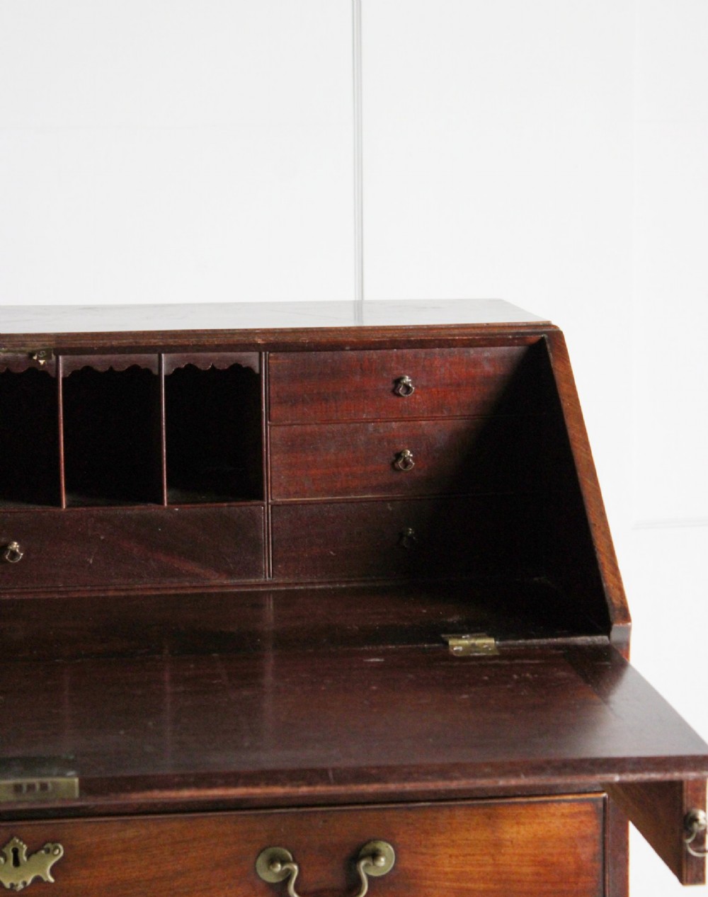 A George III mahogany fall front bureau featuring four graduated drawers with brass handles, resting on bracket feet. View VI