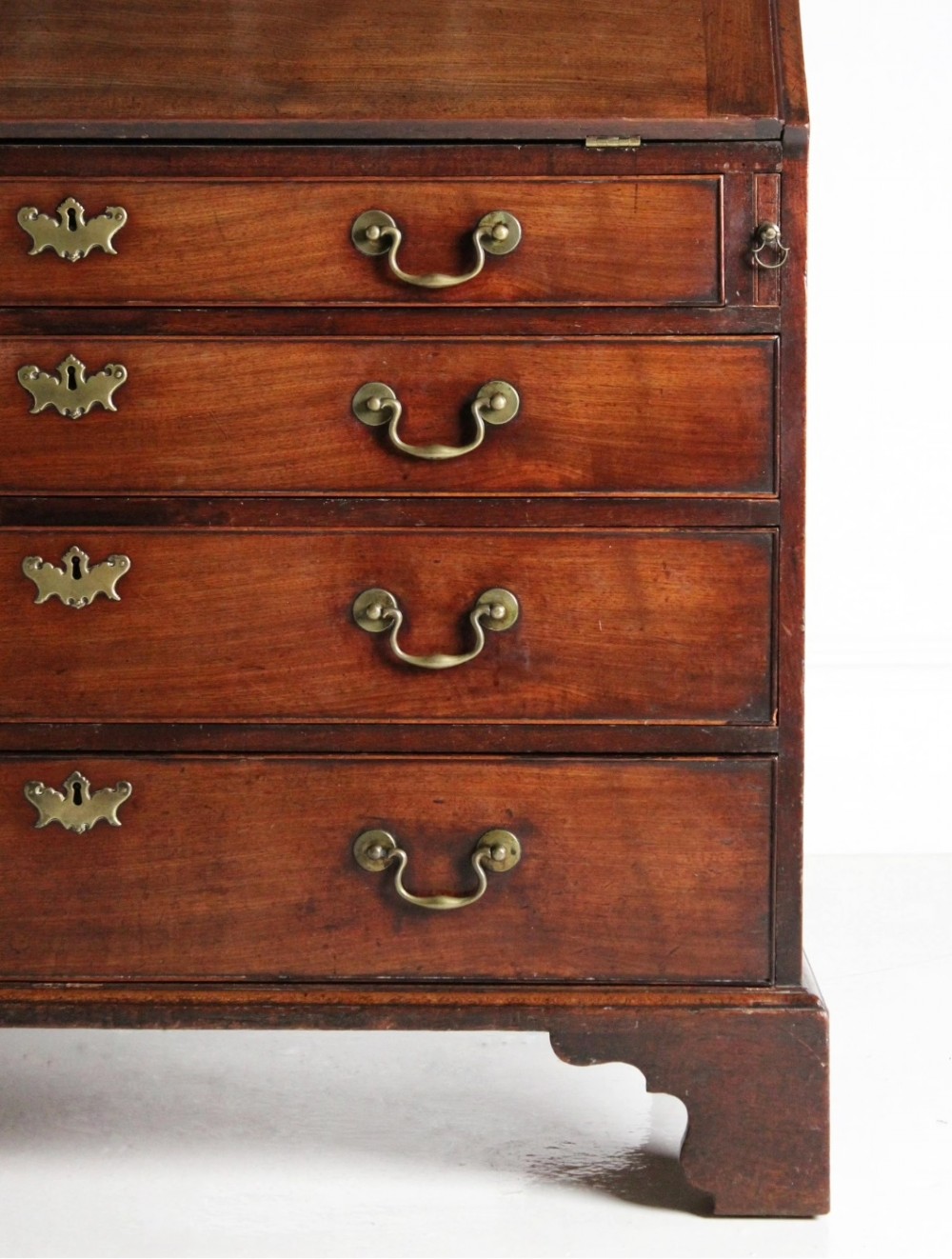 A George III mahogany fall front bureau featuring four graduated drawers with brass handles, resting on bracket feet. View VIII