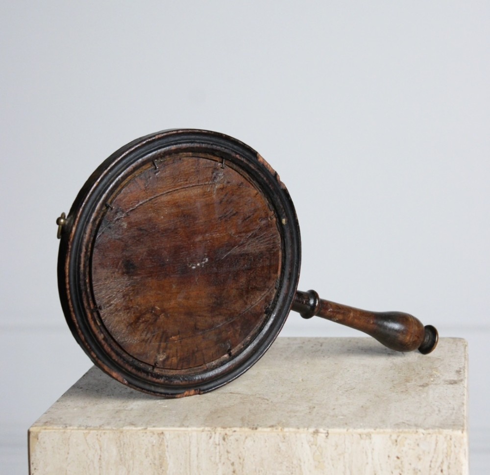 A circular Georgian wooden hand mirror with a turned handle, dark brown finish, top brass hanging loop, and foxed mirror glass. View III