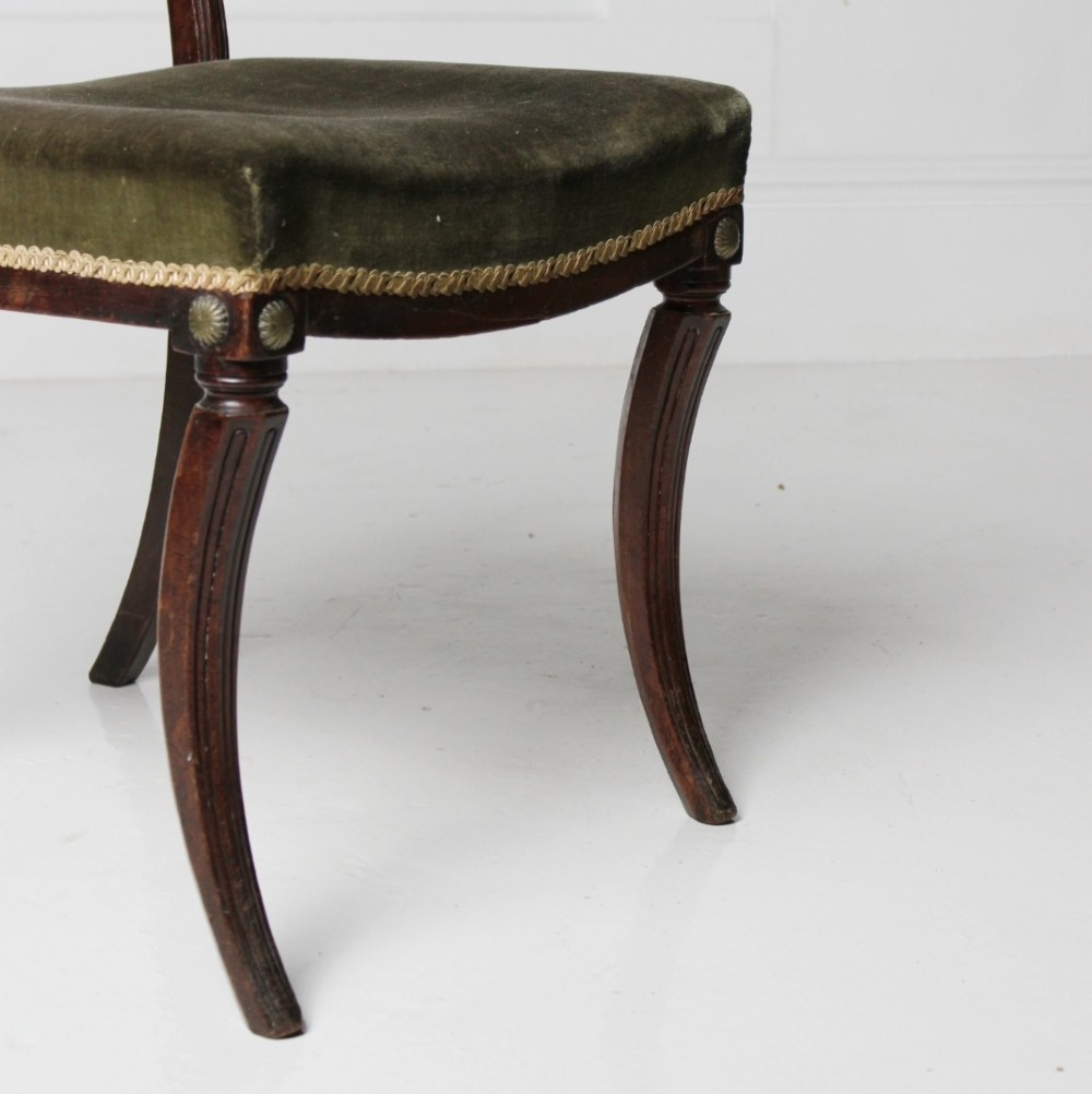 A Regency mahogany side chair with carved sabre legs, reeded frame, and olive green velvet upholstered seat with braid trim. View V