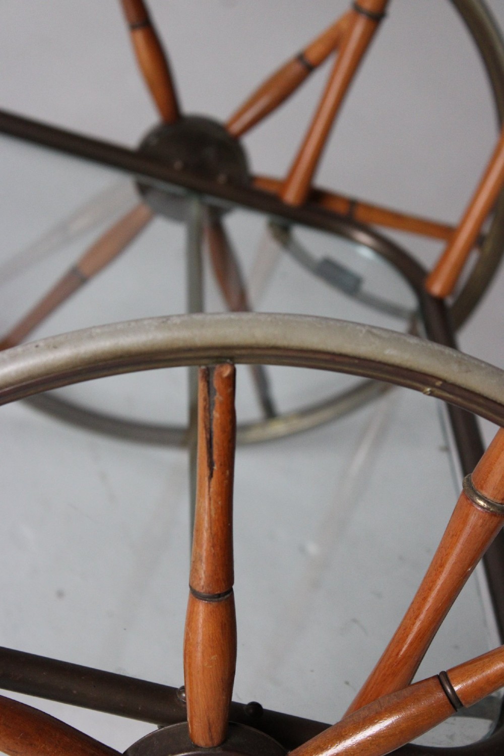 A two-tier mid-century drinks trolley featuring a faux bamboo brass and wood frame, clear glass shelves, two large spoked wheels, and small rear castors. View II