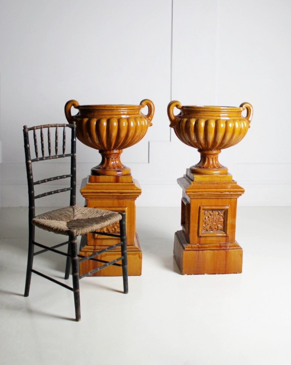 Large ochre glazed majolica urns on plinths