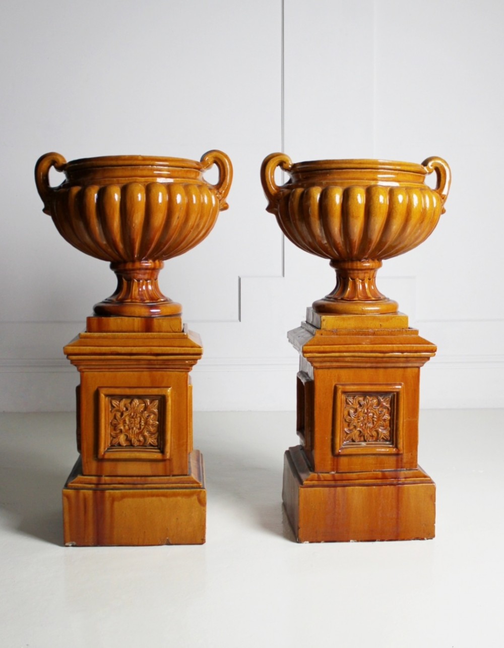 Large ochre glazed majolica urns on plinths View II