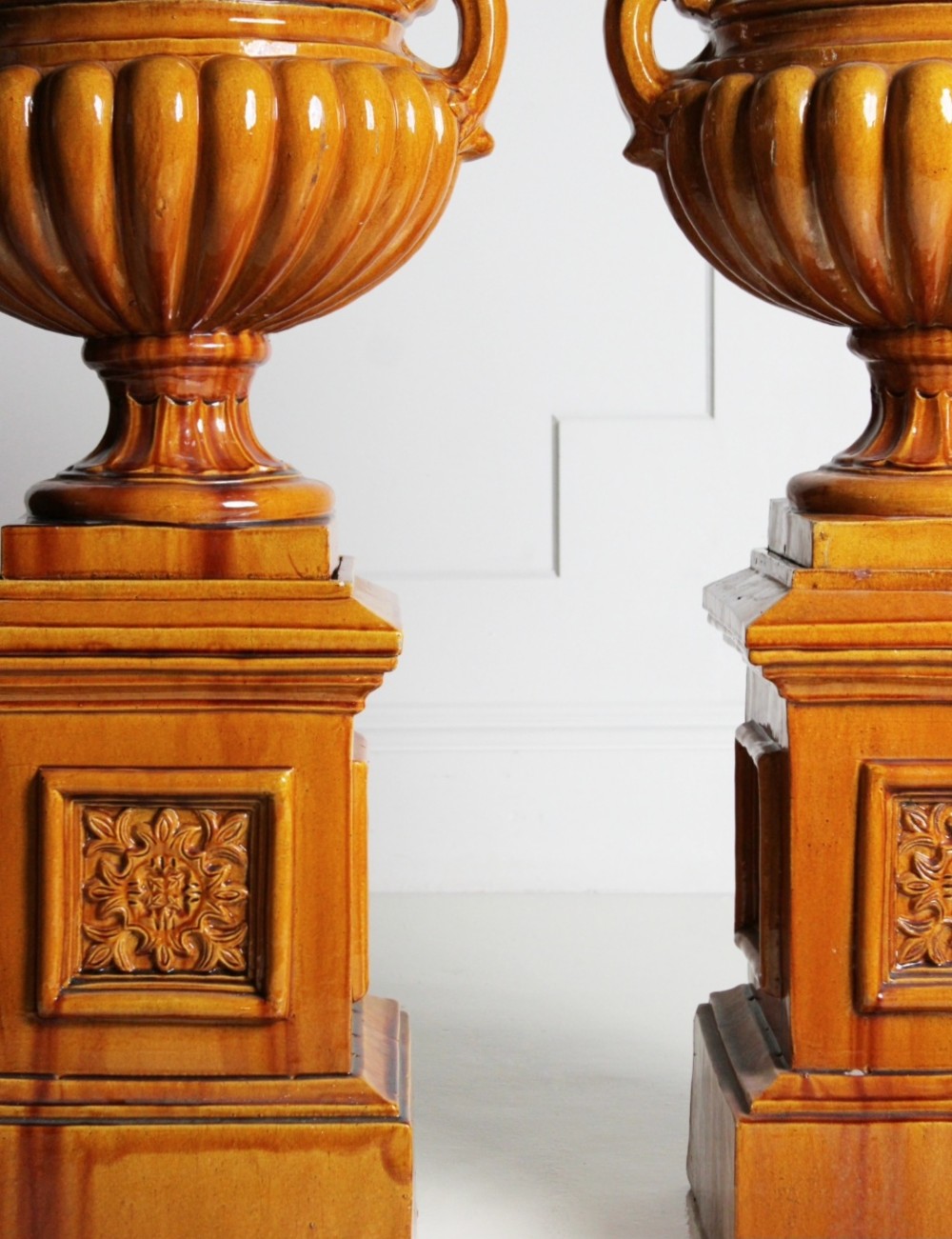 Large ochre glazed majolica urns on plinths View III