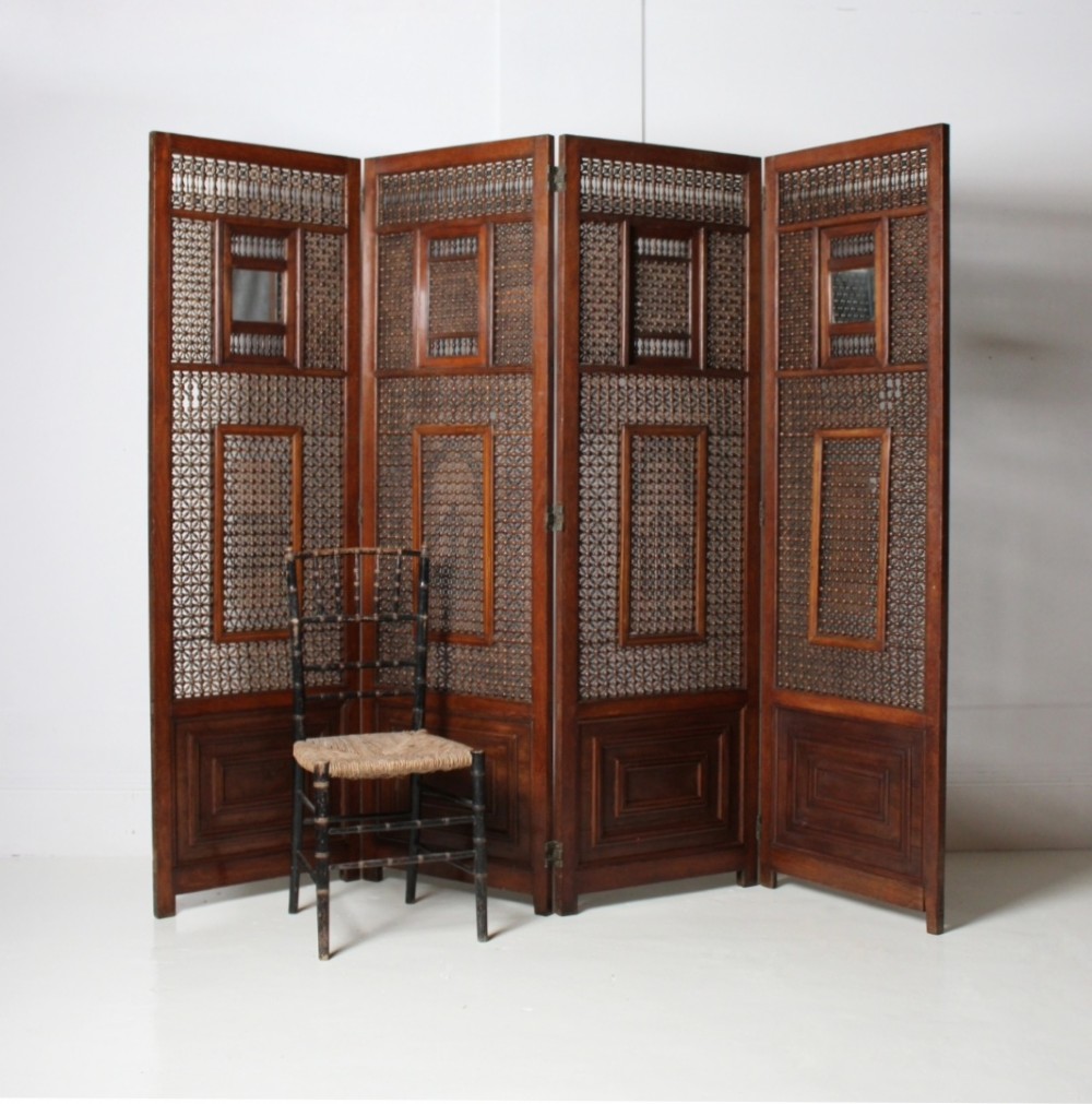 A four-panel dark hardwood folding screen featuring intricate geometric mashrabiya latticework panels above carved recessed bottom sections.