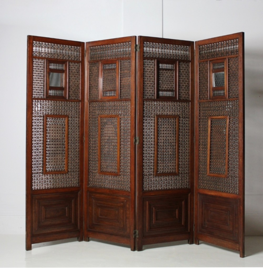 A four-panel dark hardwood folding screen featuring intricate geometric mashrabiya latticework panels above carved recessed bottom sections. View III