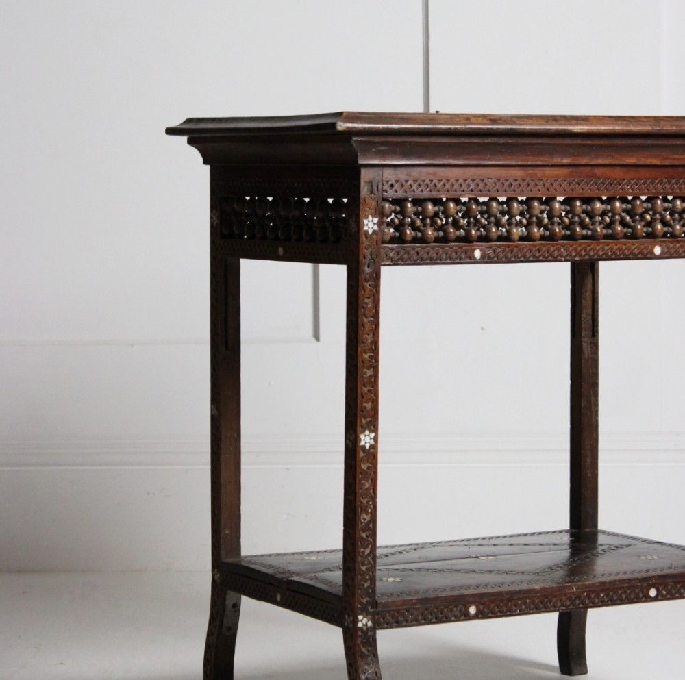 A 19th-century dark brown wooden Syrian two-tier side table featuring intricate carving, mother-of-pearl inlay, and turned lattice friezes. View III
