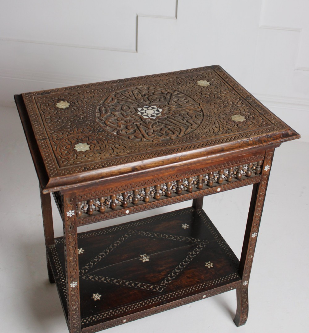 A 19th-century dark brown wooden Syrian two-tier side table featuring intricate carving, mother-of-pearl inlay, and turned lattice friezes. View V