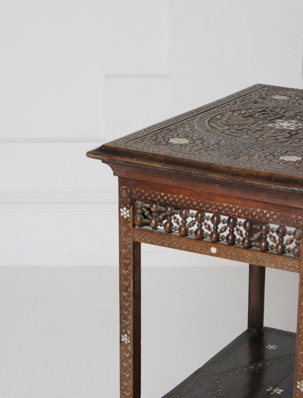 A 19th-century dark brown wooden Syrian two-tier side table featuring intricate carving, mother-of-pearl inlay, and turned lattice friezes. View VI