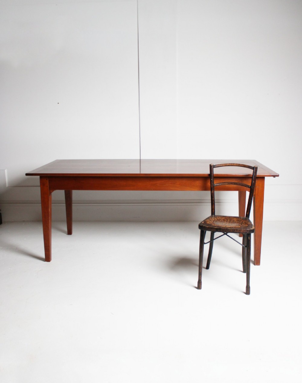 A rectangular French cherrywood dining table featuring tapered legs, a plain apron, and an end drawer with a dark circular pull knob. View II