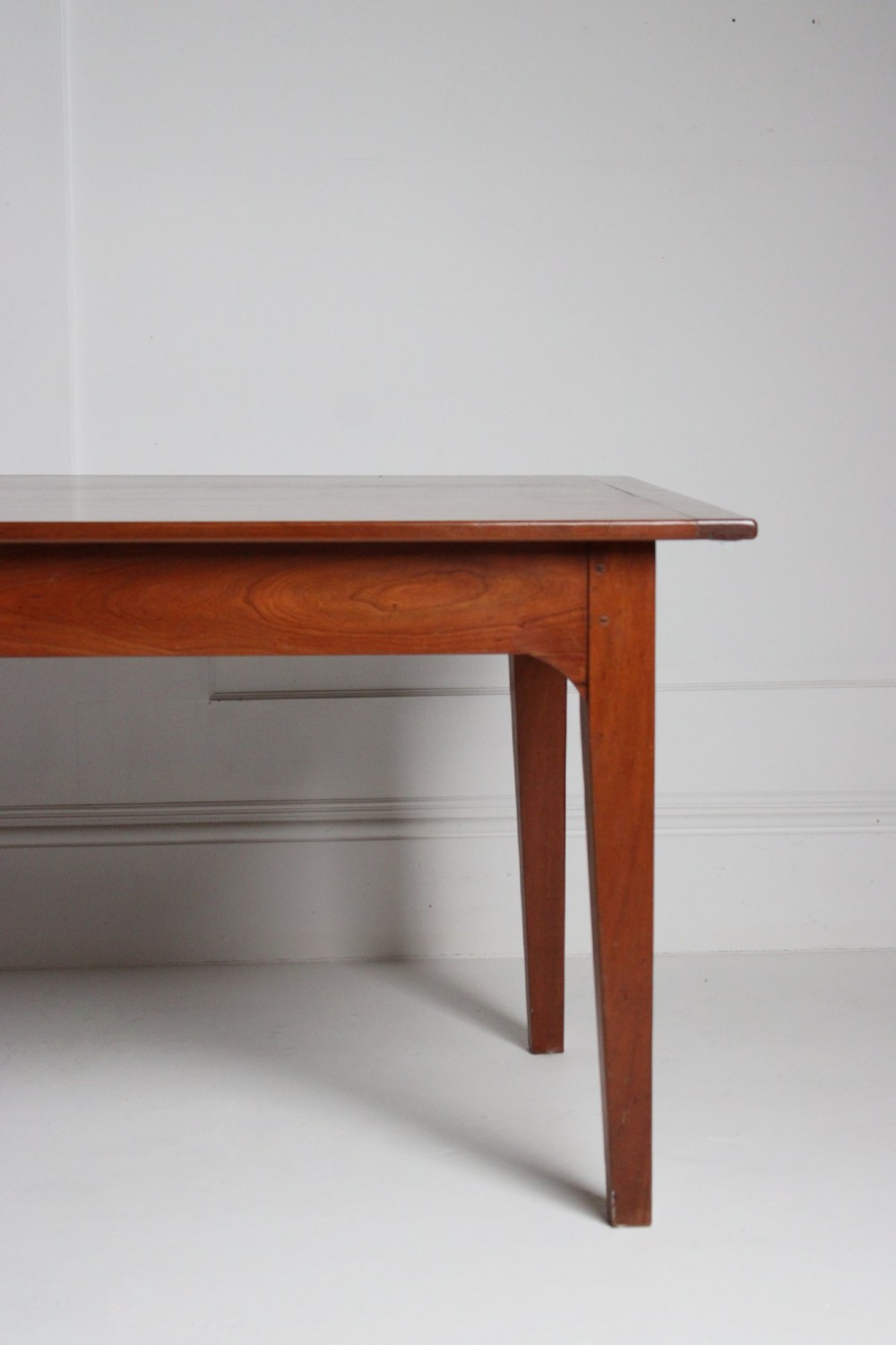 A rectangular French cherrywood dining table featuring tapered legs, a plain apron, and an end drawer with a dark circular pull knob. View III