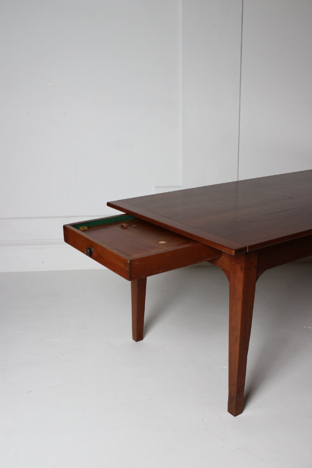 A rectangular French cherrywood dining table featuring tapered legs, a plain apron, and an end drawer with a dark circular pull knob. View V
