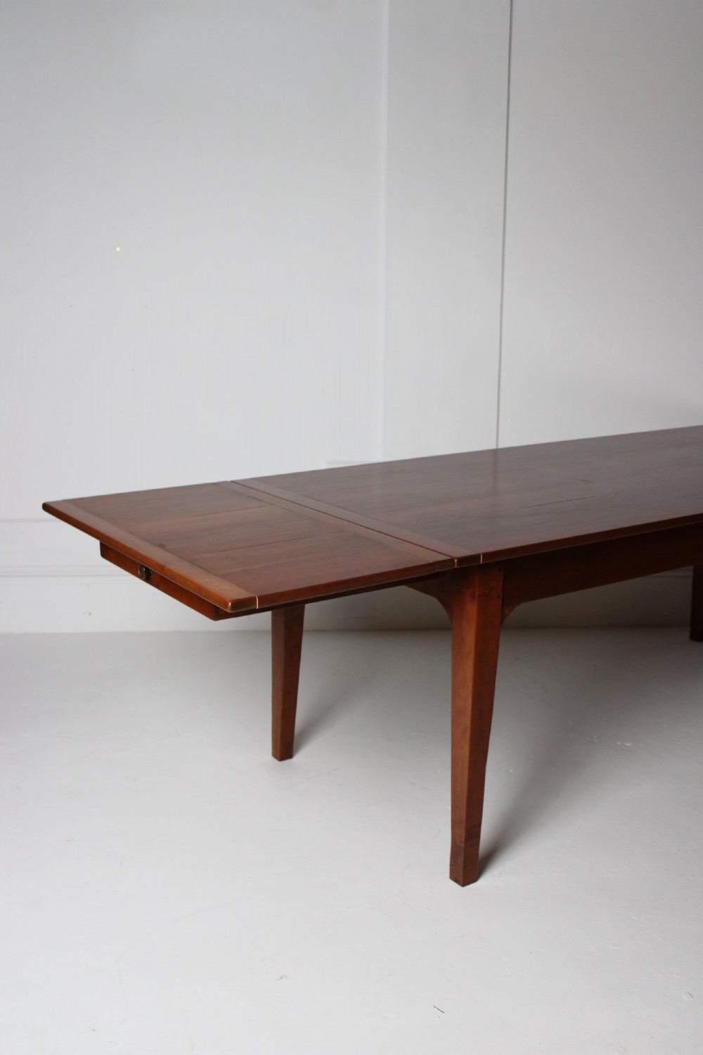 A rectangular French cherrywood dining table featuring tapered legs, a plain apron, and an end drawer with a dark circular pull knob. View VI