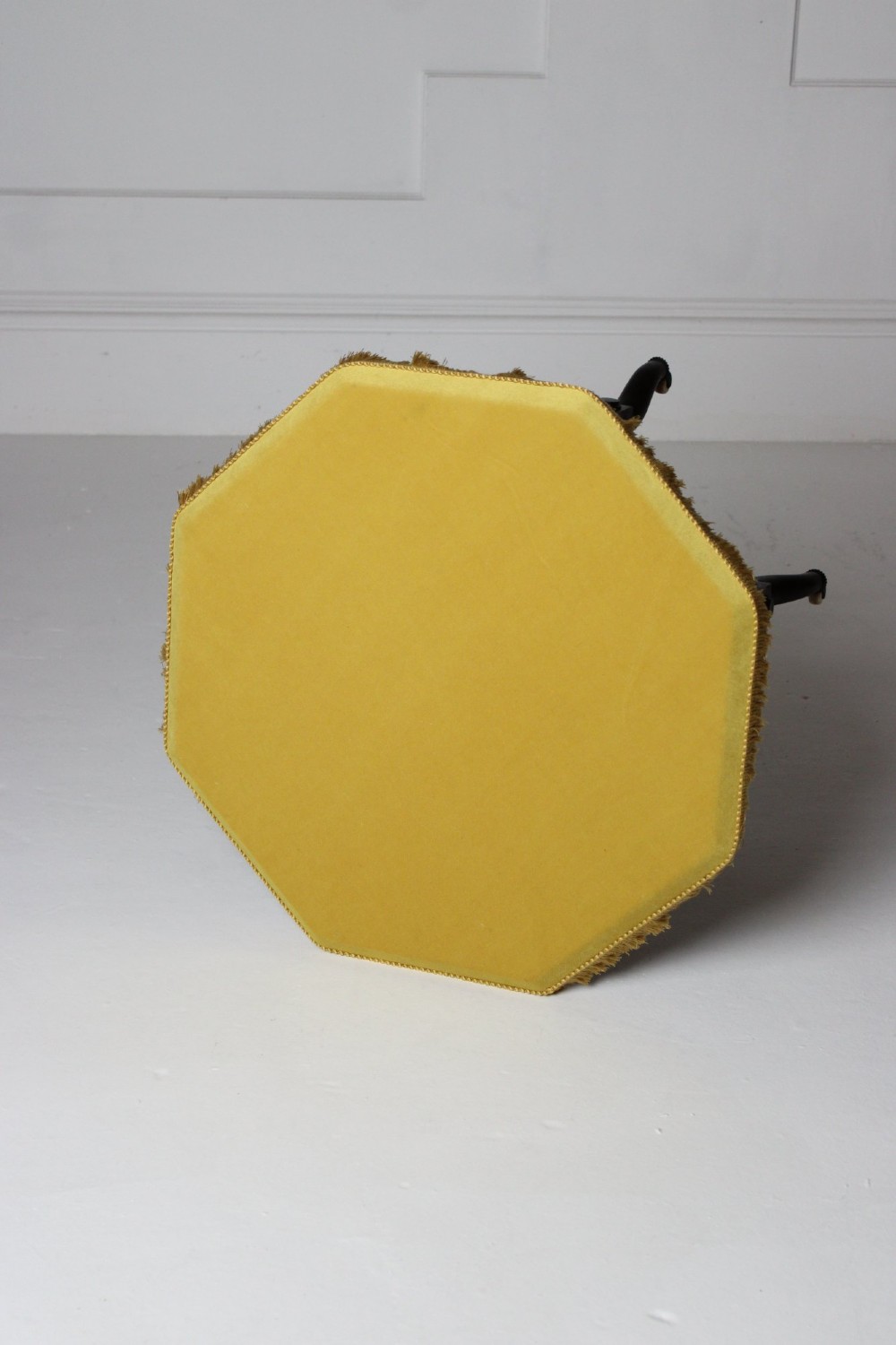 A dark timber Aesthetic Movement side table featuring turned legs, splayed feet on castors, an intricate lower stretcher, and a yellow fabric-covered top finished with fringe trim. View V