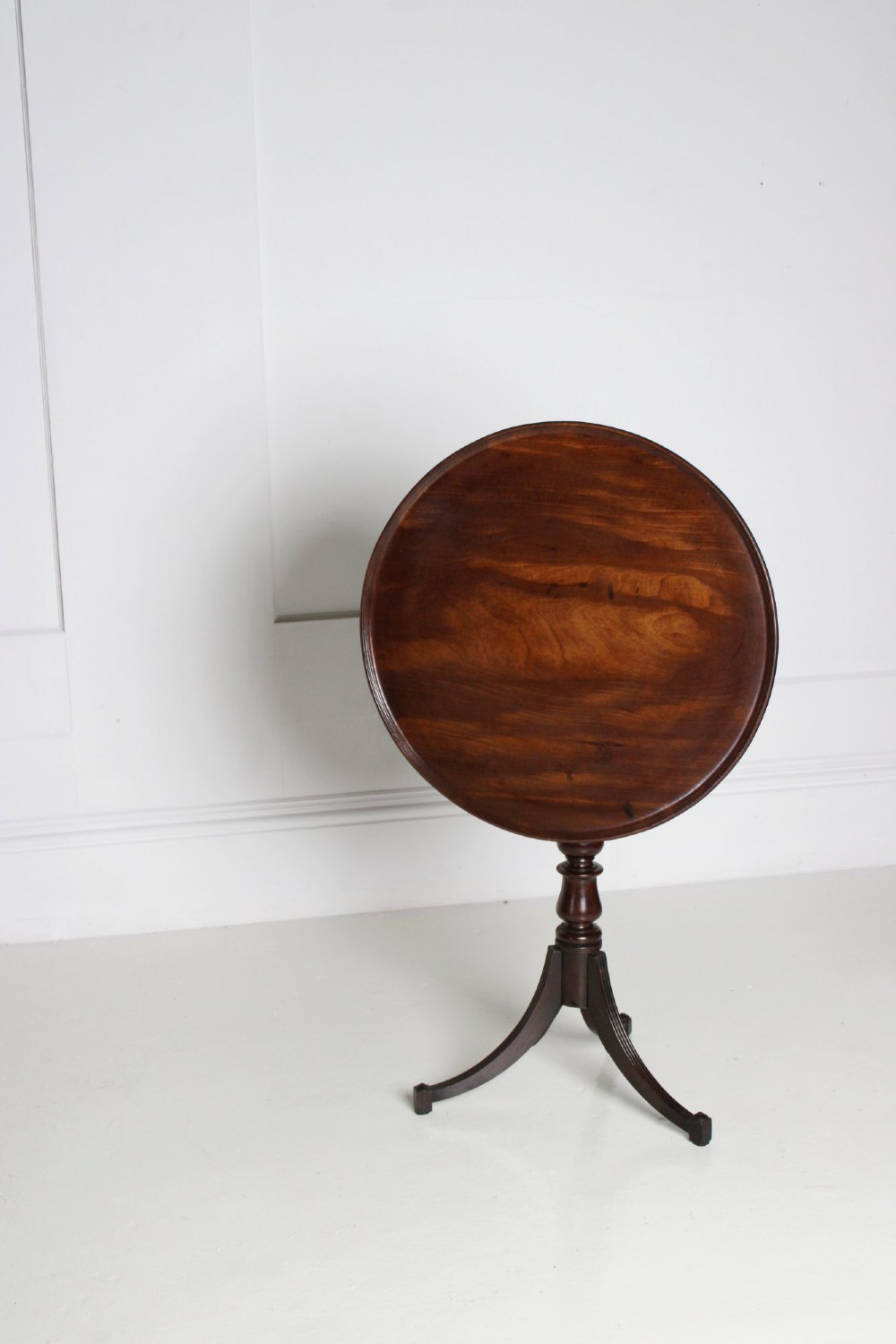 An antique Regency mahogany wine table featuring a rounded dish top on a turned pedestal stem and tripod splayed legs. View II