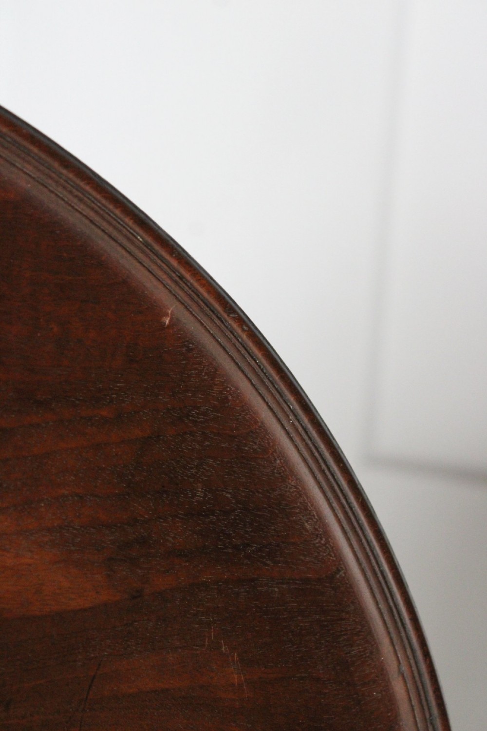 An antique Regency mahogany wine table featuring a rounded dish top on a turned pedestal stem and tripod splayed legs. View IV