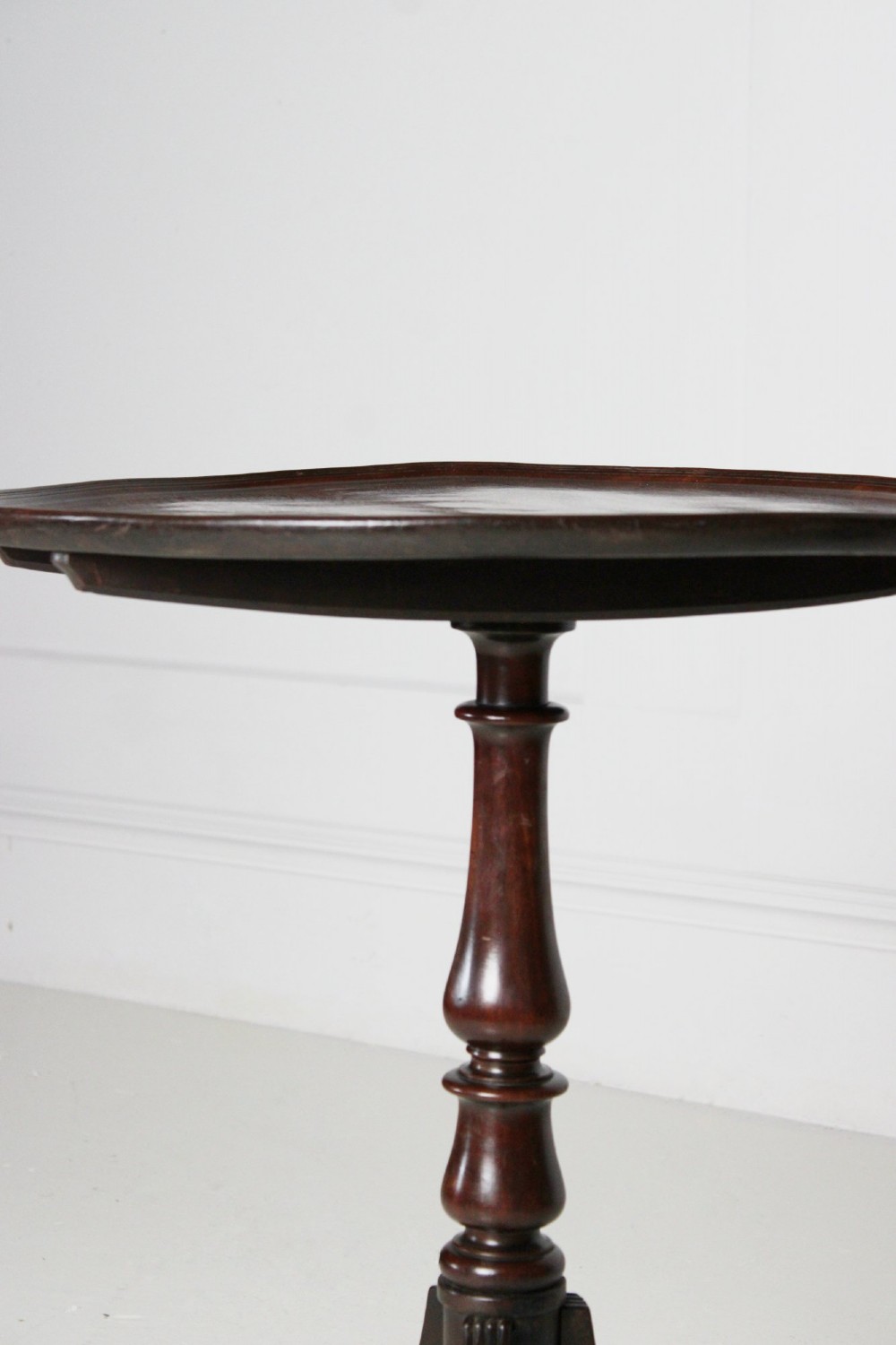 An antique Regency mahogany wine table featuring a rounded dish top on a turned pedestal stem and tripod splayed legs. View VI