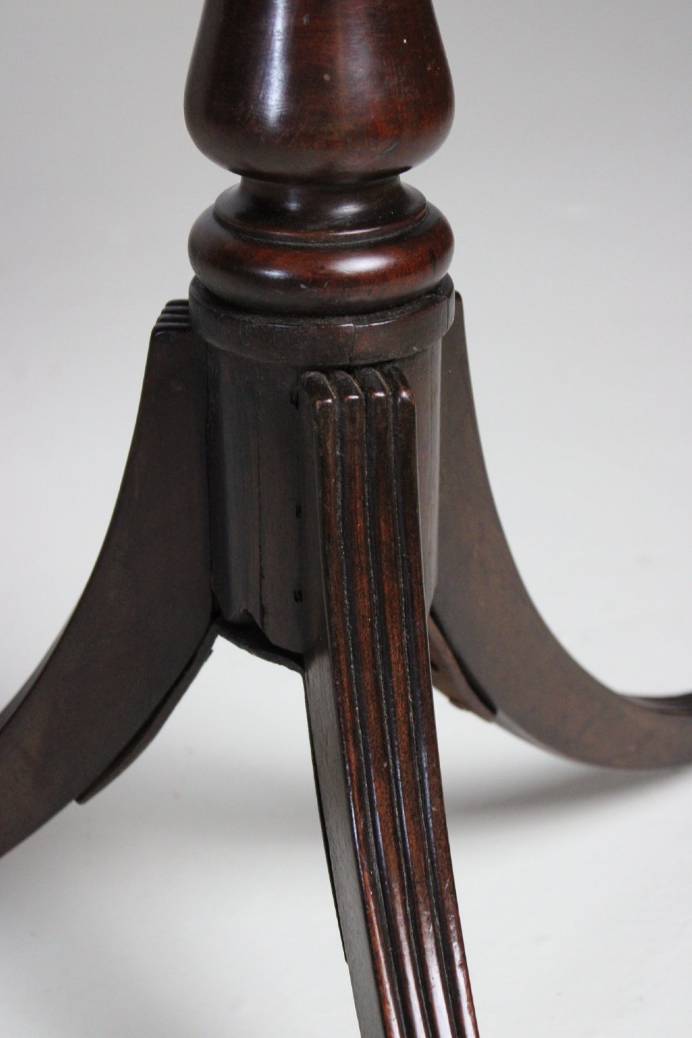 An antique Regency mahogany wine table featuring a rounded dish top on a turned pedestal stem and tripod splayed legs. View VII