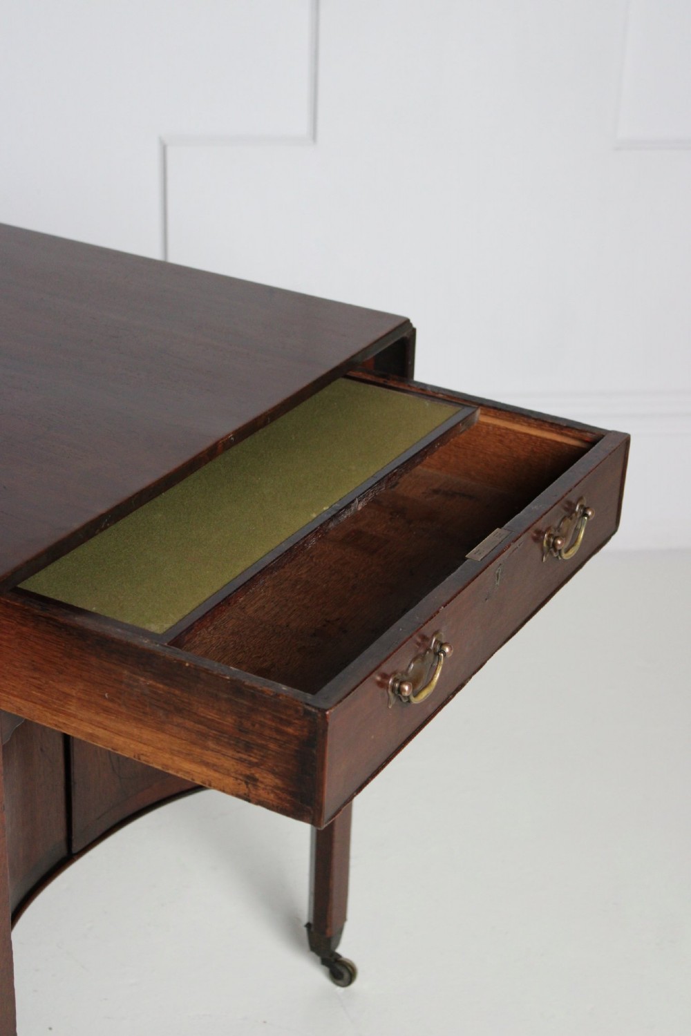 A George III mahogany side table featuring drop leaves, a single top drawer with brass handles, a concave lower cupboard, and square tapered legs on castors. View IV