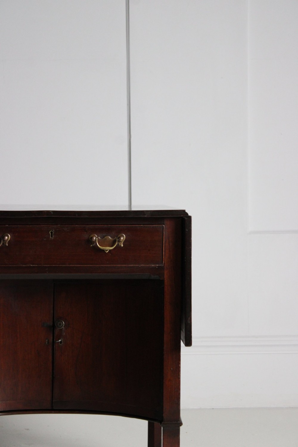 A George III mahogany side table featuring drop leaves, a single top drawer with brass handles, a concave lower cupboard, and square tapered legs on castors. View VIII