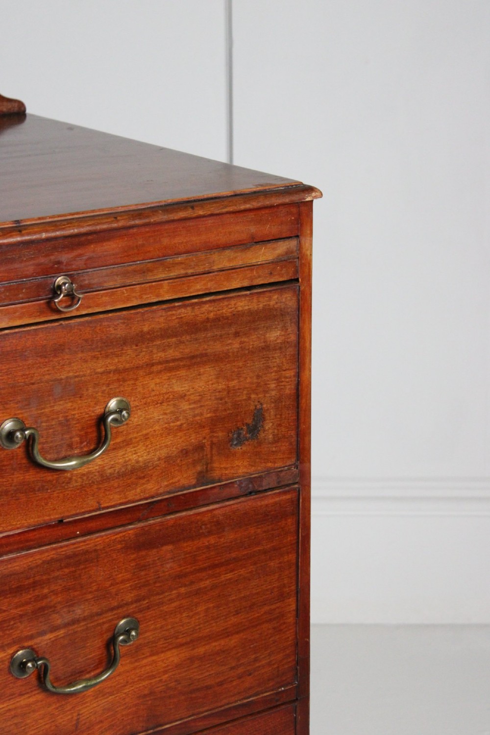 A George III mahogany chest of drawers featuring three graduated long drawers with brass swan-neck handles and bracket feet. View VII