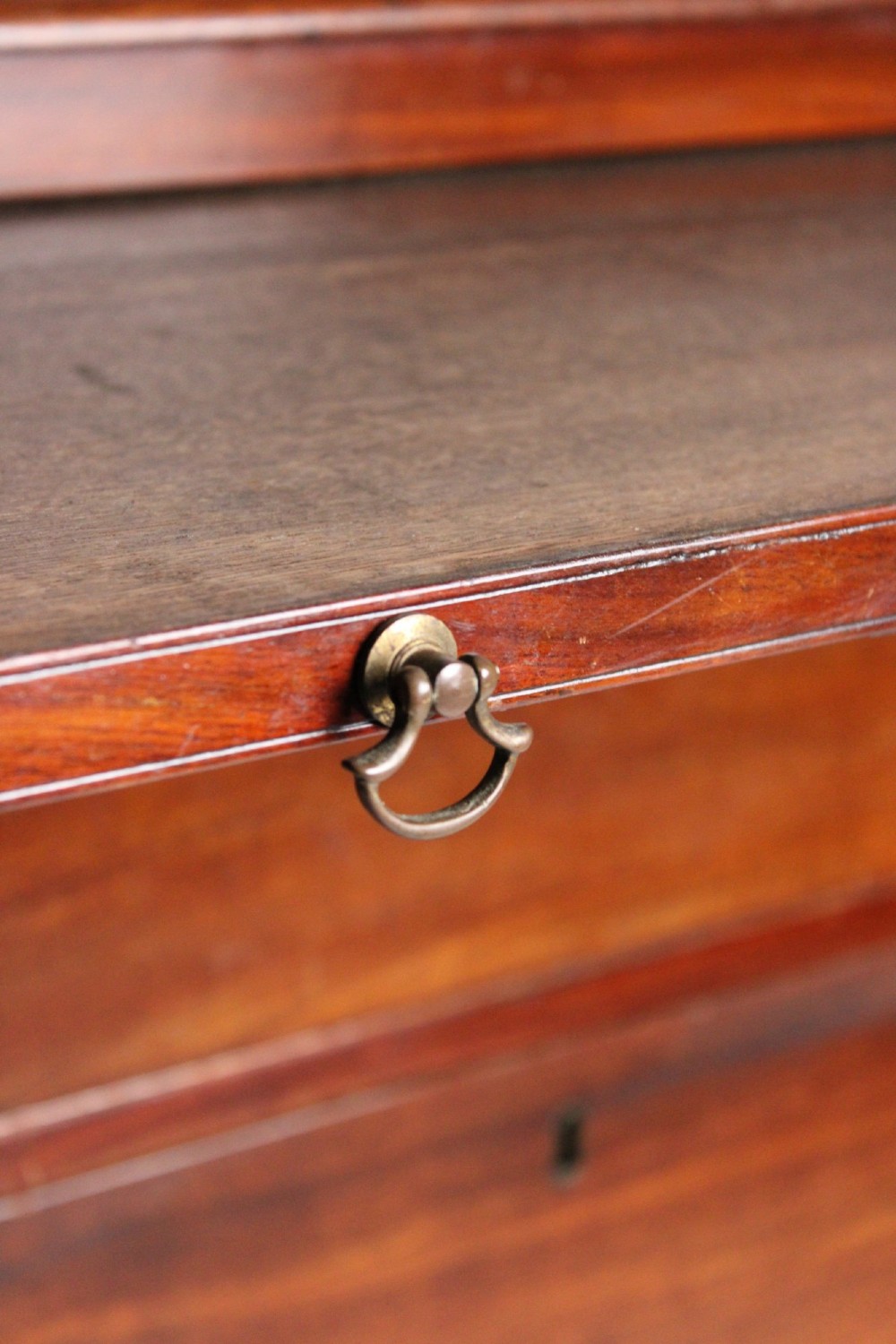 A George III mahogany chest of drawers featuring three graduated long drawers with brass swan-neck handles and bracket feet. View VIII