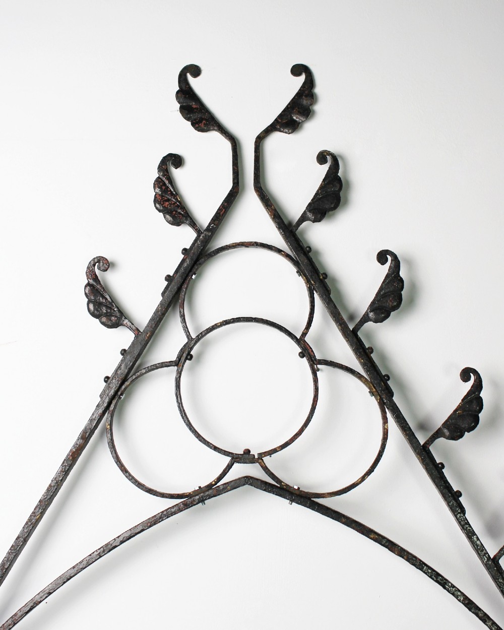 A tall Victorian Gothic Revival iron arch with a pointed apex, decorative crockets along the outer edges, and circular tracery within the upper pediment. View II