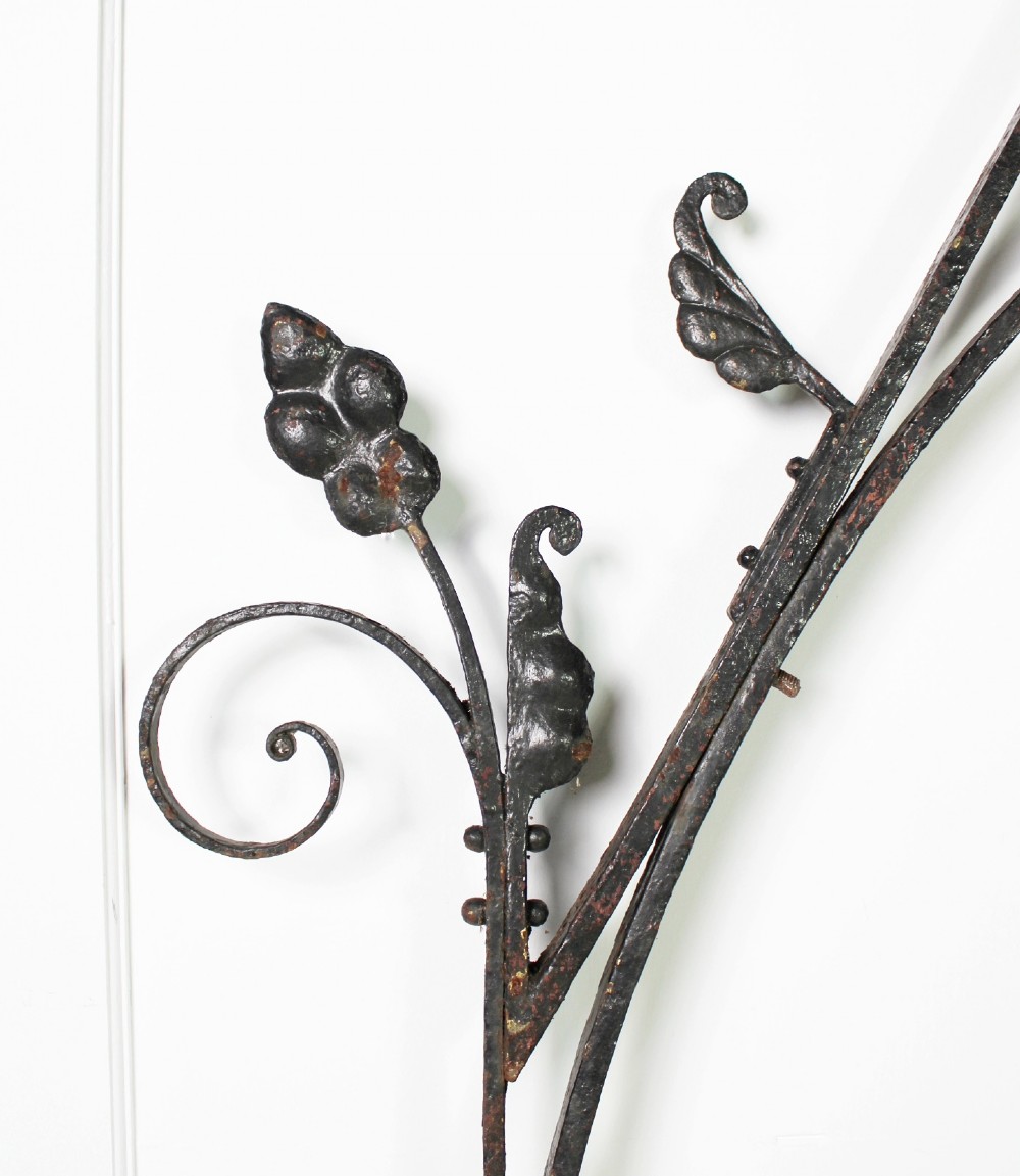 A tall Victorian Gothic Revival iron arch with a pointed apex, decorative crockets along the outer edges, and circular tracery within the upper pediment. View III