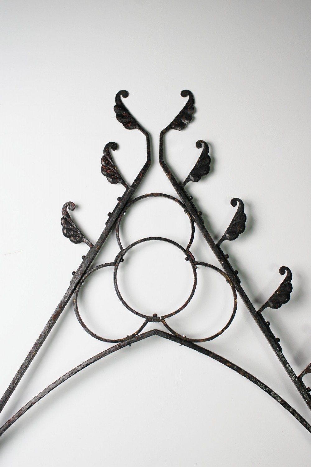 A tall Victorian Gothic Revival iron arch with a pointed apex, decorative crockets along the outer edges, and circular tracery within the upper pediment. View XIII