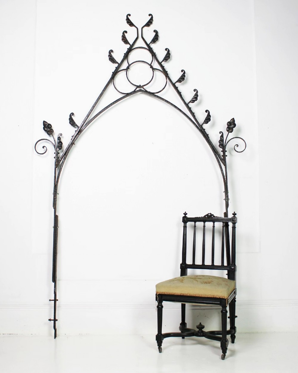A tall Victorian Gothic Revival iron arch with a pointed apex, decorative crockets along the outer edges, and circular tracery within the upper pediment. View XIV