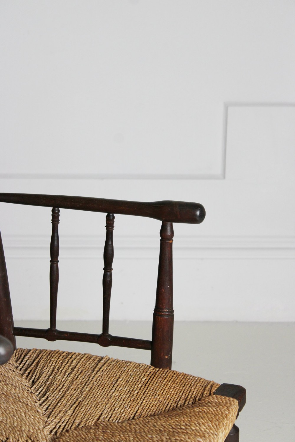 An antique dark-stained beech armchair featuring turned spindle backrests and arm supports with a natural woven rush seat. View VI