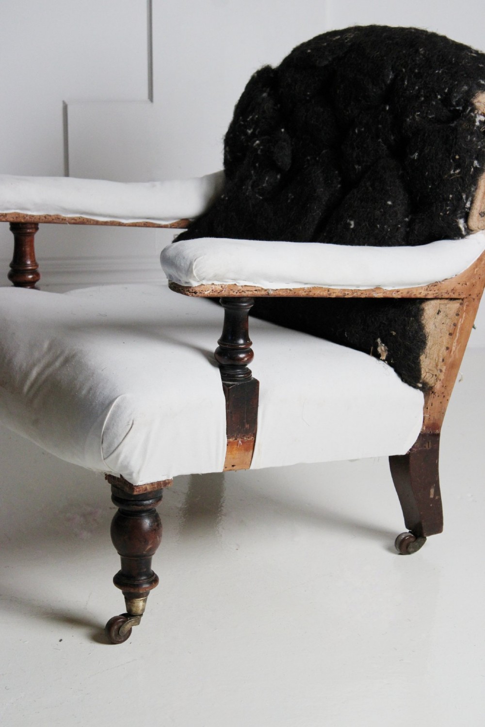 A 19th-century Victorian armchair lined in off-white calico with turned mahogany legs, brass castors, and a buttoned horsehair backrest. View II
