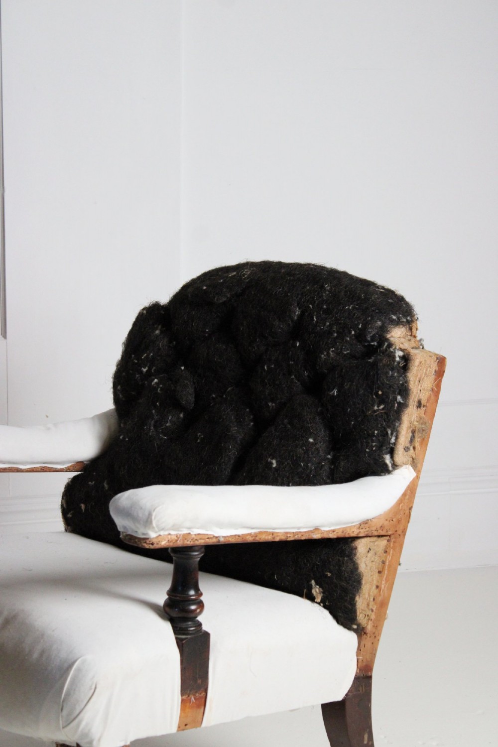 A 19th-century Victorian armchair lined in off-white calico with turned mahogany legs, brass castors, and a buttoned horsehair backrest. View III