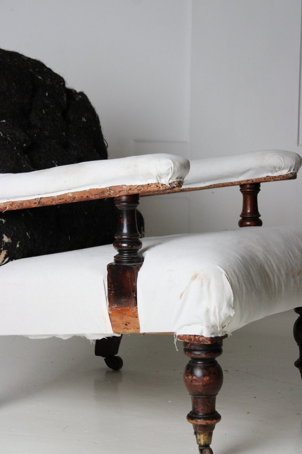 A 19th-century Victorian armchair lined in off-white calico with turned mahogany legs, brass castors, and a buttoned horsehair backrest. View VI