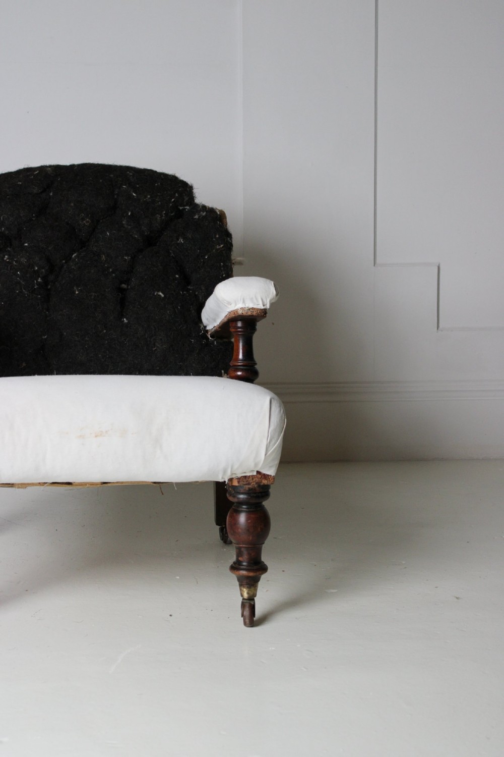A 19th-century Victorian armchair lined in off-white calico with turned mahogany legs, brass castors, and a buttoned horsehair backrest. View VII
