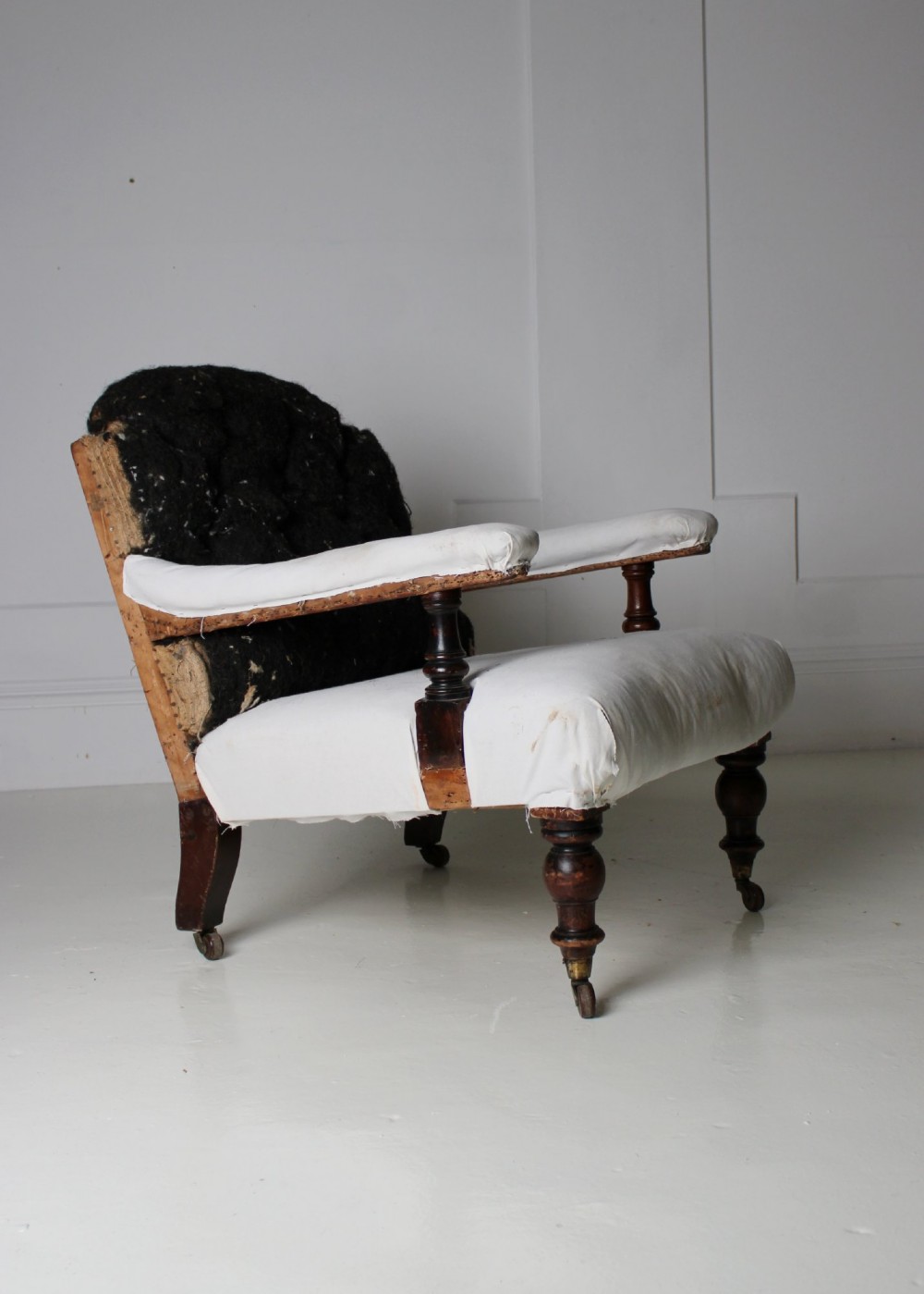 A 19th-century Victorian armchair lined in off-white calico with turned mahogany legs, brass castors, and a buttoned horsehair backrest. View VIII
