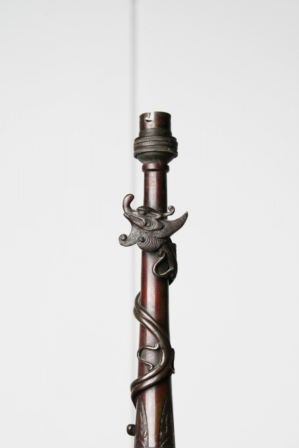 An antique dark bronze table lamp base featuring a sculpted dragon wrapped around a slender stem above a rounded base. View II