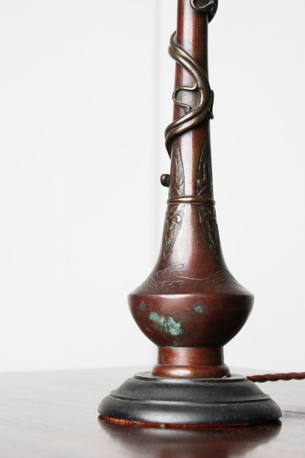 An antique dark bronze table lamp base featuring a sculpted dragon wrapped around a slender stem above a rounded base. View V