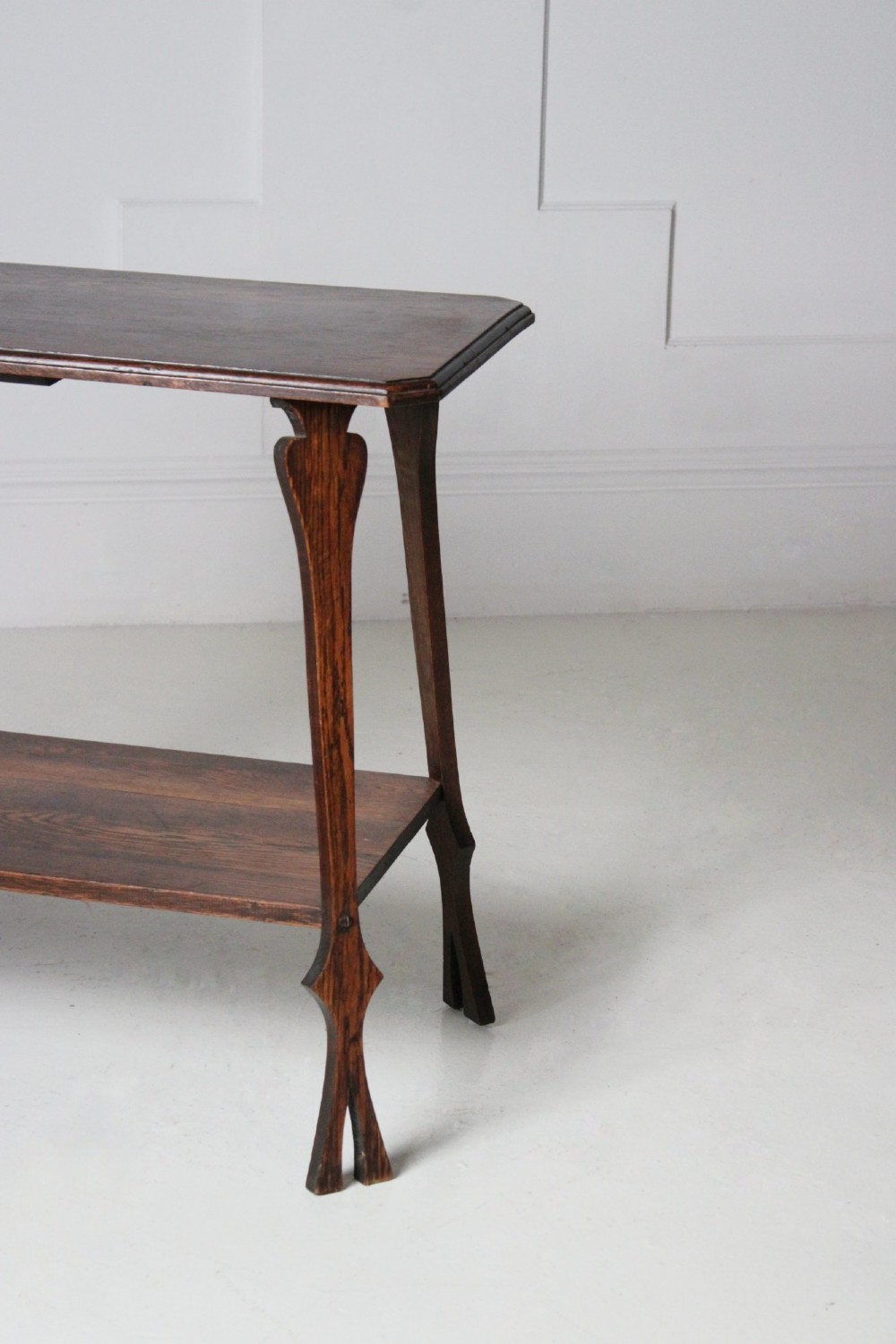 An Arts and Crafts dark oak side table featuring a rectangular top, a lower tier shelf, and stylized tapered legs with spade cutouts. View III