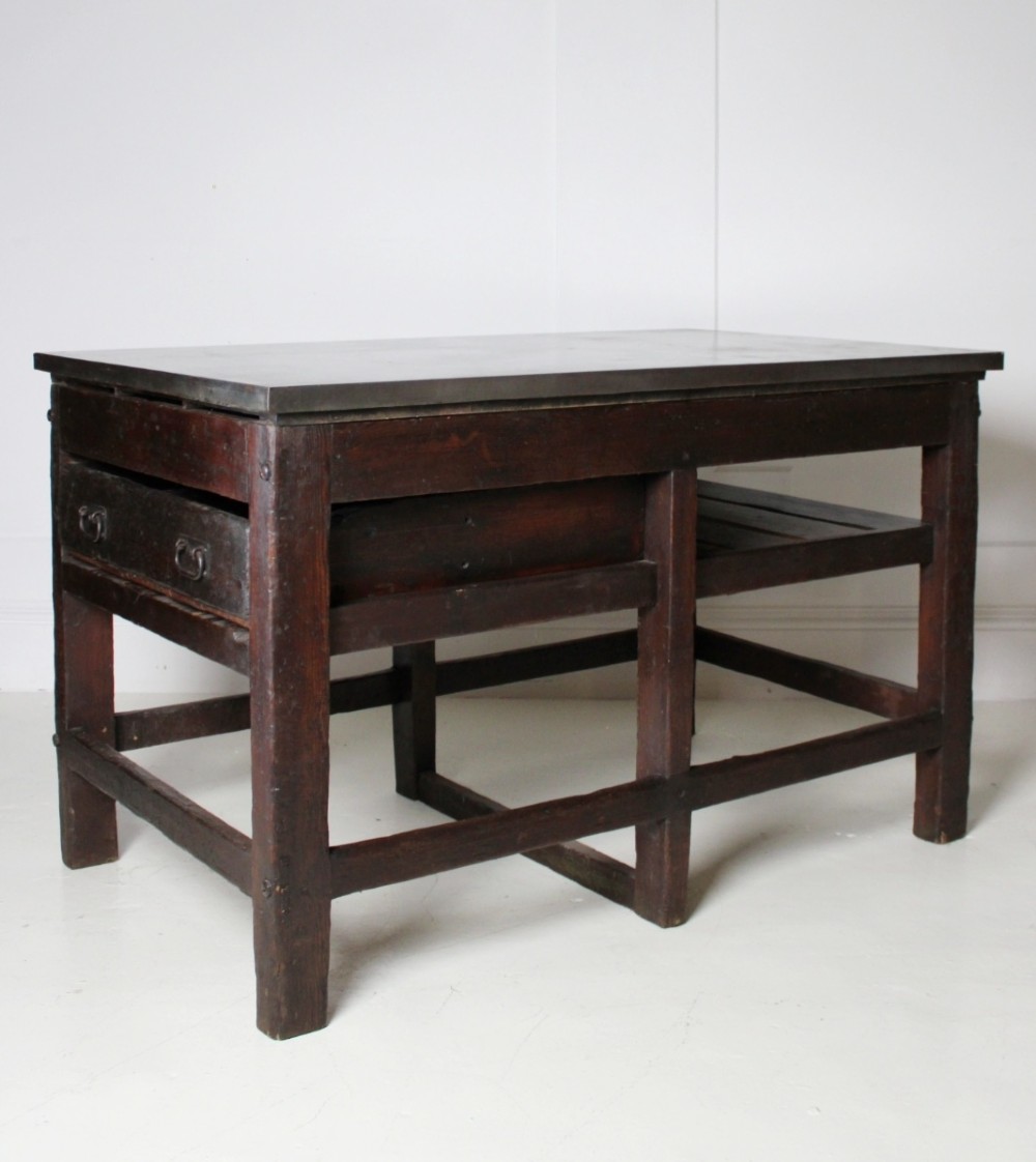 A heavy Victorian dark wood industrial typesetting table featuring a flat metal surface, deep storage drawers, and robust square legs. View III