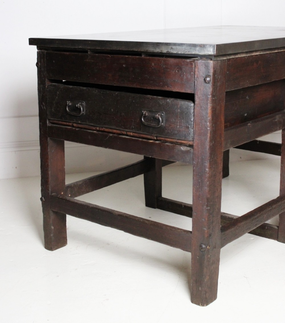 A heavy Victorian dark wood industrial typesetting table featuring a flat metal surface, deep storage drawers, and robust square legs. View VI