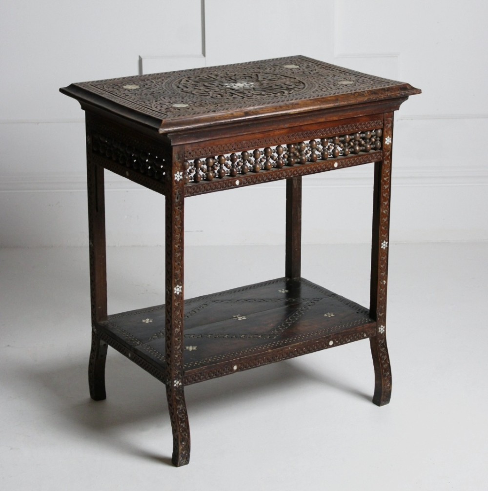 A 19th-century two-tier Syrian side table made from dark walnut with geometric mother-of-pearl inlay and carved openwork lattice panels.